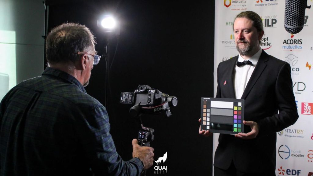 Un cameraman demande à un acteur de tenir un panneau pour effectuer des réglages de couleur sur la caméra